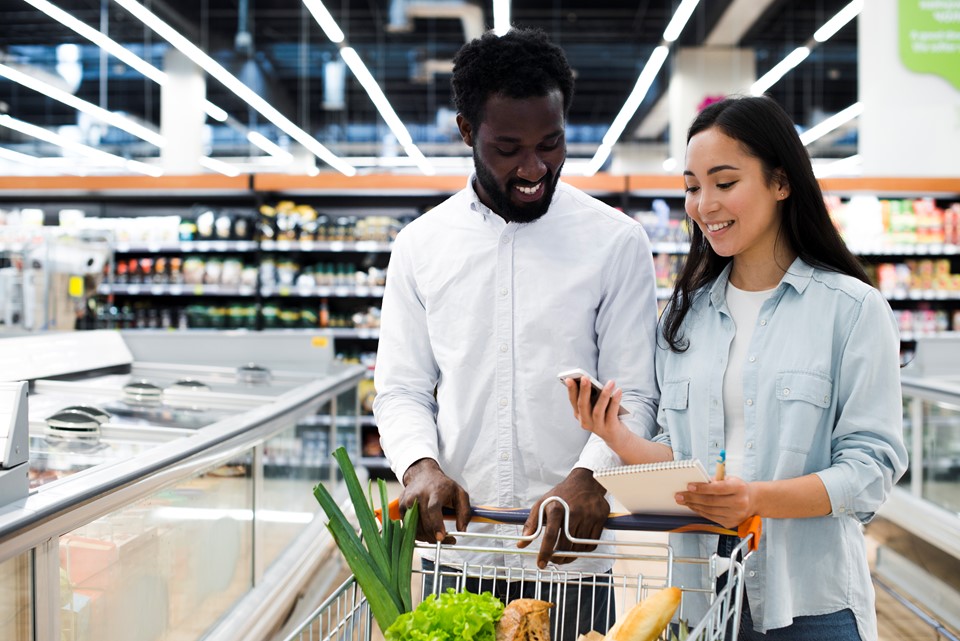 cheerful-couple-with-shopping-cart-checking-mobile-shopping-list-supermarket