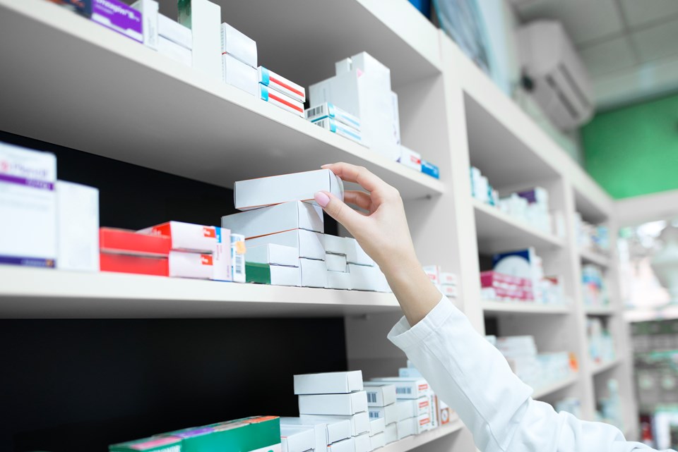 closeup-vista-da-mao-do-farmaceutico-tirando-a-caixa-de-remedios-da-prateleira-da-farmacia