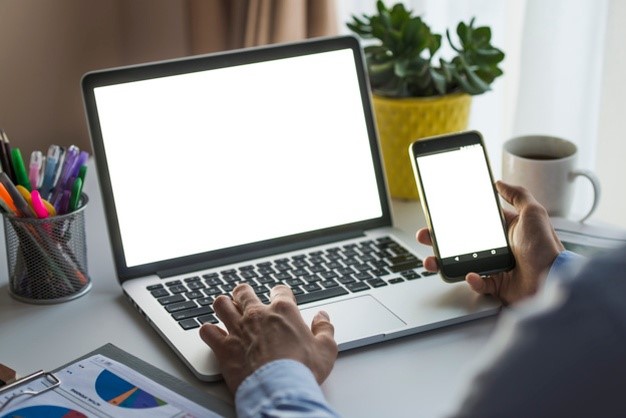 homem-usando-smartphone-e-laptop-no-escritorio_23-2147772289