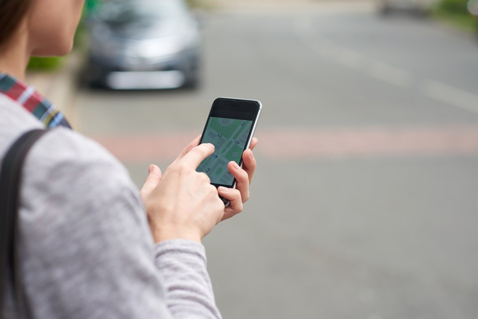 shoulder-view-unrecognizable-person-tracking-taxi-mobile-app