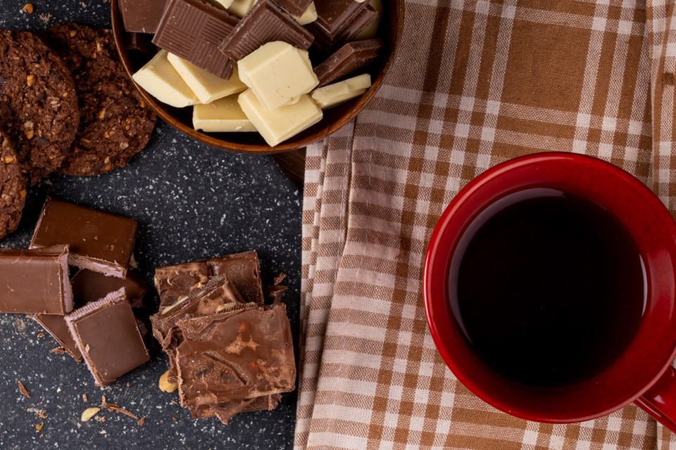 vista-superior-de-uma-caneca-com-biscoitos-de-aveia-cha-e-pedacos-de-chocolate-escuros-e-brancos-em-uma-tigela-de-madeira-no-fundo-rustico